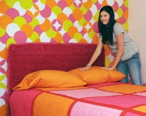 A preteen girl happily making her bed in her very colorful room.